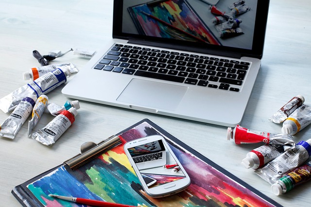 Laptop on desk with a painting and painting tools